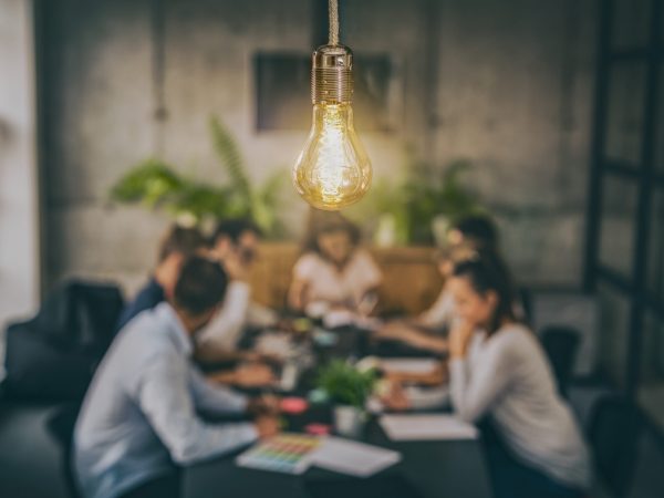 Young business people are discussing together a new startup project. A glowing light bulb as a new idea.